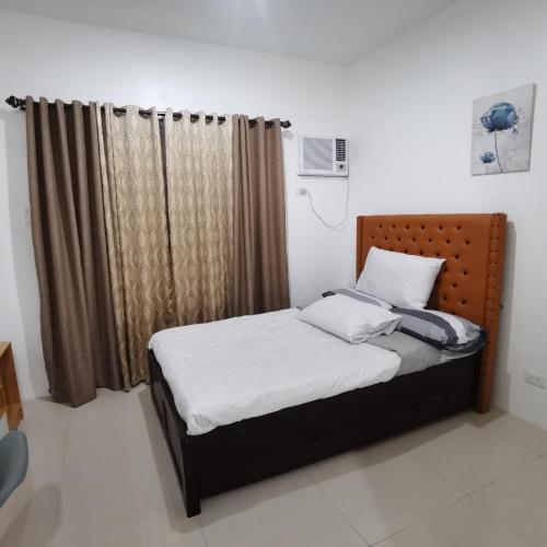 1 dormitorio con cama y ventana en Affordable Condo w/ Shower Heater and Wi-Fi, en Minglanilla