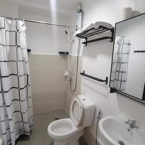 Baño blanco con aseo y lavamanos en Affordable Condo w/ Shower Heater and Wi-Fi, en Minglanilla