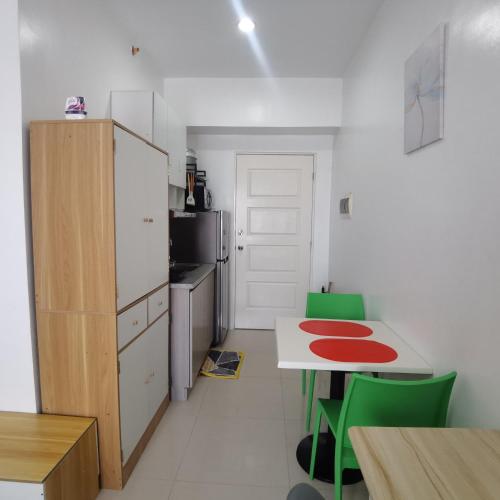 a small kitchen with a table and green chairs at Affordable Condo w/ Shower Heater and Wi-Fi in Minglanilla
