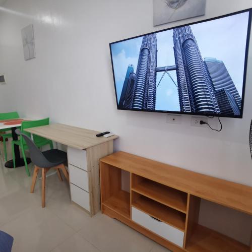 a room with a desk and a flat screen tv on a wall at Affordable Condo w/ Shower Heater and Wi-Fi in Minglanilla