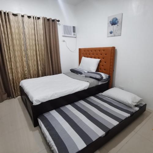 two twin beds in a room with a window at Affordable Condo w/ Shower Heater and Wi-Fi in Minglanilla