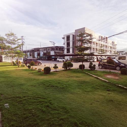 a park with cars parked in front of a building at Affordable Condo w/ Shower Heater and Wi-Fi in Minglanilla
