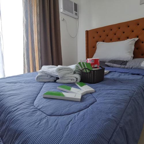 a bed with a blue bedspread with towels on it at Affordable Condo w/ Shower Heater and Wi-Fi in Minglanilla