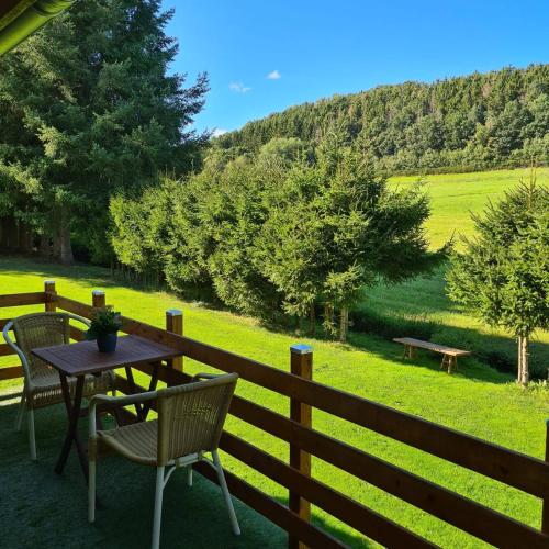 a table and chairs on a fence with a view of a field at Guesthouse Wallenborn - Caravan Chalet in Wallenborn