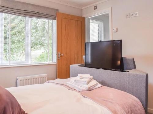 Gorstage Meadows Luxury 2 Bedroom Lodge in Rural Cheshire في Hartford: غرفة نوم بسرير وتلفزيون بشاشة مسطحة