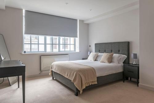 a bedroom with a bed and a desk and two windows at The Eyre Suite Six - Farringdon - by Frankie in London