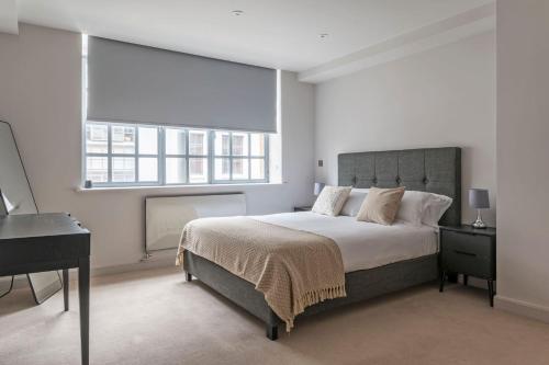 a bedroom with a bed and a desk and two windows at Amigos Nest - Farringdon - by Frankie Says in London