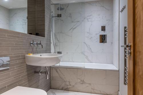 ein weißes Bad mit einem Waschbecken und einer Dusche in der Unterkunft Amigos Nest - Farringdon - by Frankie Says in London