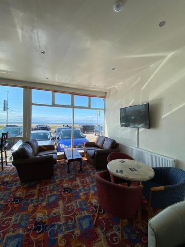a living room with couches and chairs and a flat screen tv at South Beach Hotel in Blackpool
