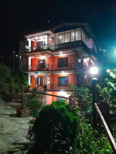 a large building with a balcony at night at Himchuli Guest House in Bandīpur