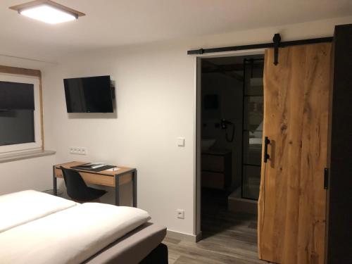 a bedroom with a bed and a desk and a sliding door at Hotel Weilerhof in Dormagen