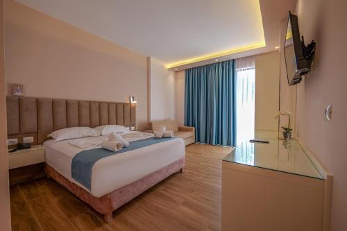 a hotel room with a large bed and a television at HOTEL DENOEL in Ksamil