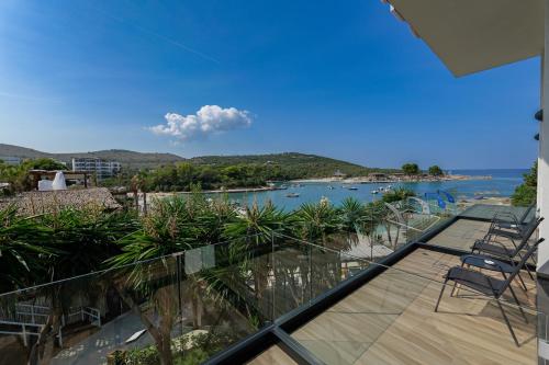 a balcony with chairs and a view of the water at HOTEL DENOEL in Ksamil