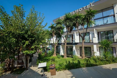 a building with palm trees in front of it at HOTEL DENOEL in Ksamil