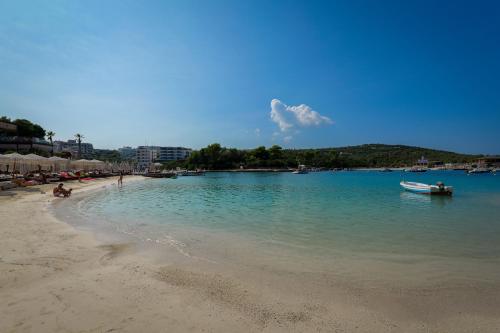 a beach with a boat in the water at HOTEL DENOEL in Ksamil