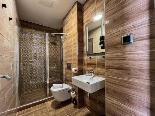 a bathroom with a toilet and a sink and a shower at AM HOTEL WELLNESS **** in Rimavská Sobota