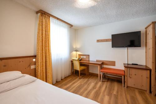 a hotel room with a bed and a desk and a television at Seehof Reduit in Davos