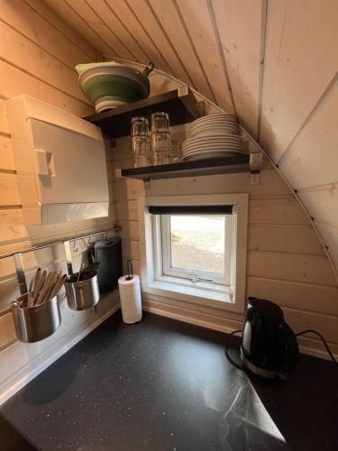 a small kitchen with a window in a tiny house at Helle Aktivitetshotel in Årre