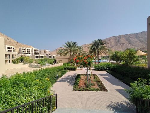 a walkway with flowers and palm trees in a resort at Apartment, Muscat Bay in Muscat