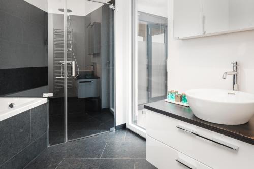 a bathroom with a sink and a glass shower at Kaiser Apartments - Wohnpark Graz-Gösting in Graz
