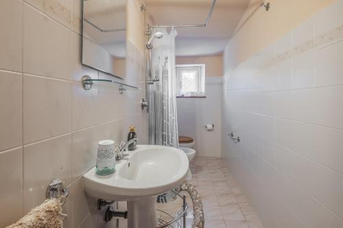 a white bathroom with a sink and a toilet at La pieve - Gerani in Pereta