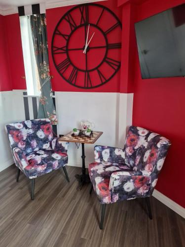 a room with two chairs and a clock on the wall at The Mad Hatter's Guestrooms in Oxford