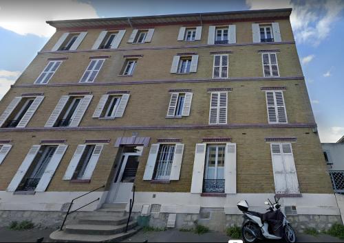 une moto garée devant un grand bâtiment en briques dans l'établissement Appartement 2 pièces tout équipé très lumineux, à Nanterre