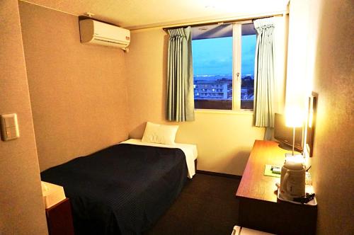 Habitación de hotel con cama y ventana en HOTEL THE NEXT KANKU en Sennan