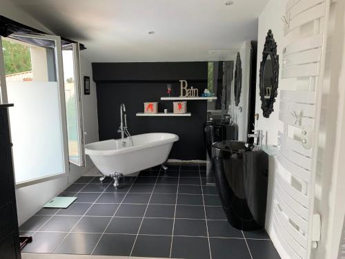 La salle de bains est pourvue d'une baignoire blanche et d'un mur noir. dans l'établissement Villa familiale, à Le Fenouiller