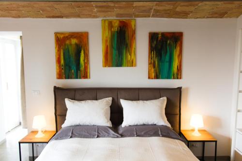 a bedroom with a bed with three paintings on the wall at Dimora Relax in Costigliole dʼAsti