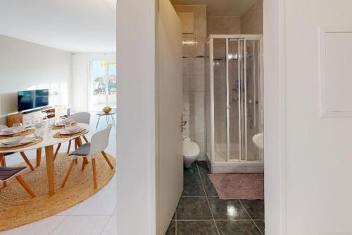 a dining room with a table and a bathroom at Casa delle Vigne: Giardino, pergola e vista lago in Minusio