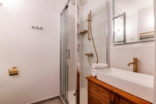 La salle de bains est pourvue d'une douche et d'un lavabo blanc. dans l'établissement Veeve - Rustic Allure, à Paris