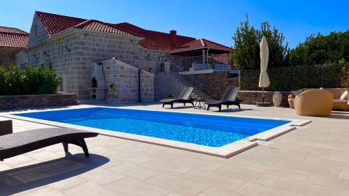 a swimming pool with two chairs and a umbrella at Villa Dalma in Čilipi