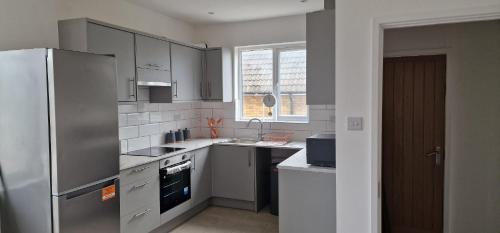 a kitchen with a refrigerator and a sink at SHM Stays Leicester. Newly Renovated!! 15 min drive from City Centre, University. 9 min Drive to Leicester City Stadium, 5 min drive to M1 & M69. 2 min walk to bus stop. in Leicester