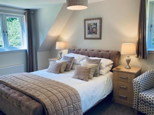 a bedroom with a large bed with two lamps and a chair at Estate Houses at Carberry Tower in Edinburgh