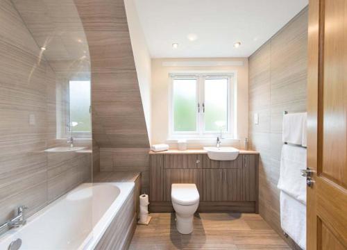 a bathroom with a tub and a toilet and a sink at Estate Houses at Carberry Tower in Edinburgh