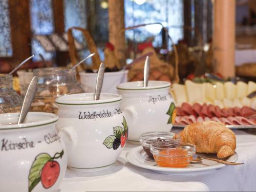 een tafel met drie bakjes jam en een bord met eten bij Hotel Pension Sonnegg in Saltusio