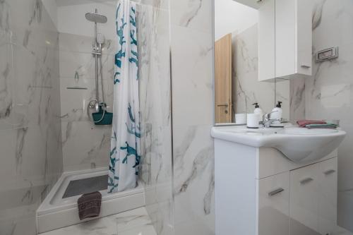 a white bathroom with a sink and a shower at Apartments Bella Vista in Nova Vas