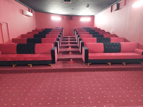 an empty cinema room with red and black chairs at Hotel Ain Safnan Room&Flats فندق عين صفنان غرف&شقق in Sanāw