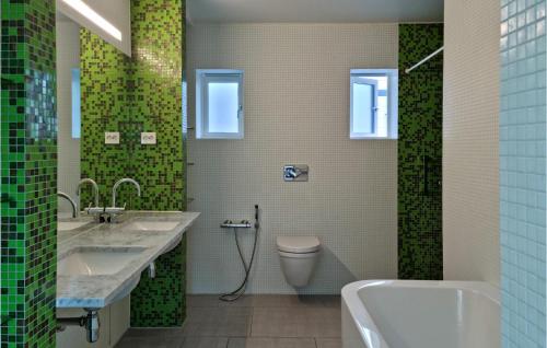 baño con 2 lavabos, aseo y azulejos verdes en Beautiful Apartment In Mandal With House Sea View en Mandal