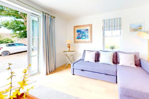 een woonkamer met een paarse bank en een raam bij Croyde Secret Garden in Croyde