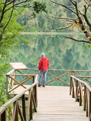 a man standing on a bridge over a lake at Cabaña Familiar de Descanso y Paseo - Puyehue in Puyehue
