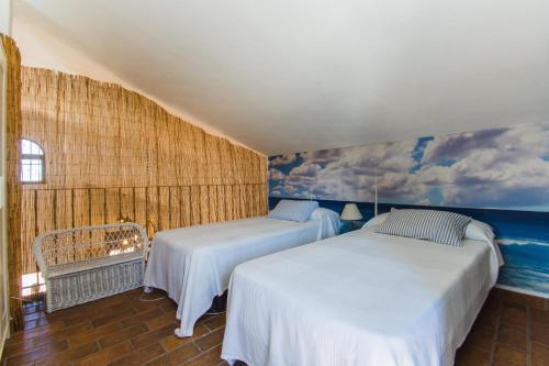 2 Betten in einem Zimmer mit Wandgemälde in der Unterkunft Villas Florida in Conil de la Frontera