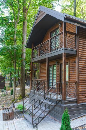 a cabin with a balcony and stairs in a forest at Готельно-ресторанний комплекс БОЖЕДАР in Vinnytsya
