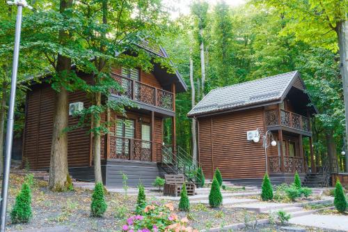 a log cabin in the woods next to a house at Готельно-ресторанний комплекс БОЖЕДАР in Vinnytsya