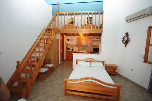 - une chambre avec un lit et un escalier en bois dans l'établissement Foinikas Rooms, à Eratini