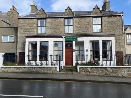 un edificio in mattoni con una porta rossa su una strada di Alder Lodge Guest House a Lerwick