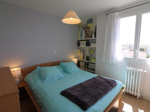 - une chambre avec un lit doté de draps bleus et une fenêtre dans l'établissement Appartement Aurillac, 2 pièces, 2 personnes - FR-1-742-389, à Aurillac