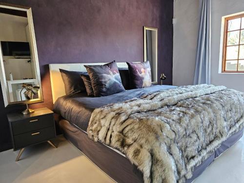 a bedroom with a bed with a faux fur blanket at The Retreat Swellendam in Swellendam