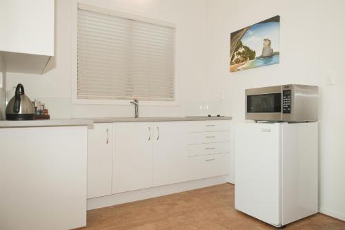 uma cozinha branca com um micro-ondas e um frigorífico em Beachfront Resort em Whitianga